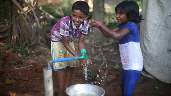 Children smiling and gathering water from well - Ecolab