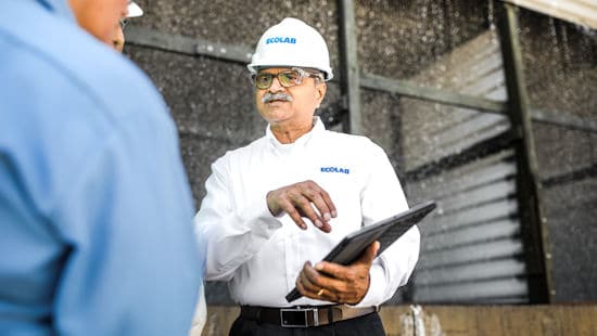 Man with clipboard and Ecolab hardhat